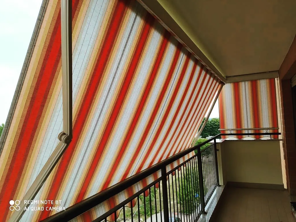 Tenda da sole a bracci con tessuto a righe su balcone