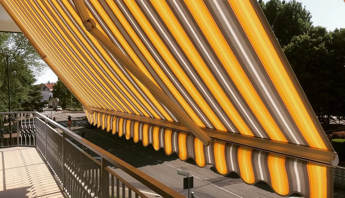 Tenda da sole a bracci gialla estesa sopra un balcone
