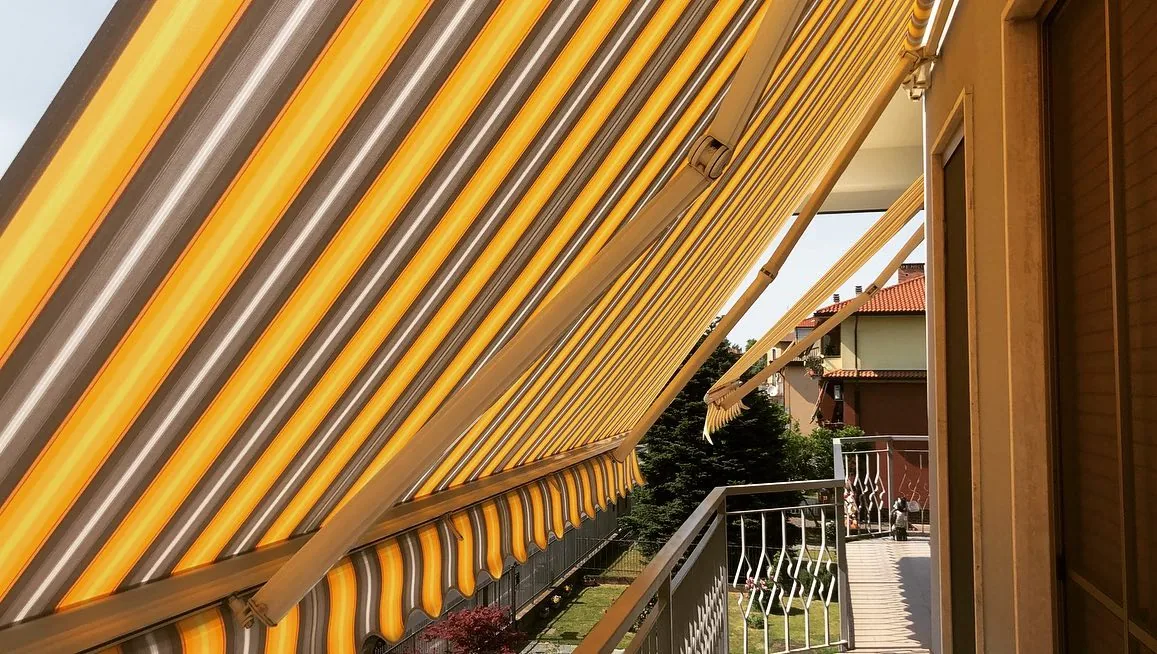 Tenda da sole a bracci con tessuto giallo su terrazzo di abitazione