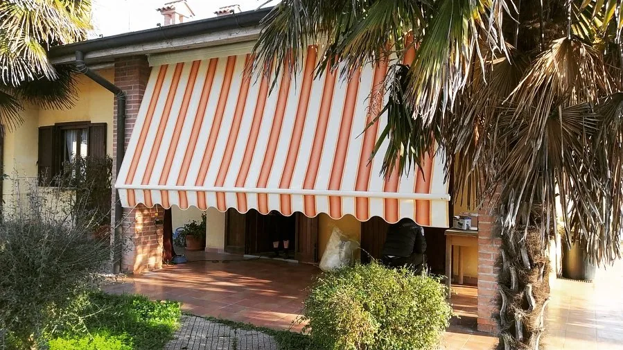 Tenda da sole a caduta a righe su facciata di villa con giardino