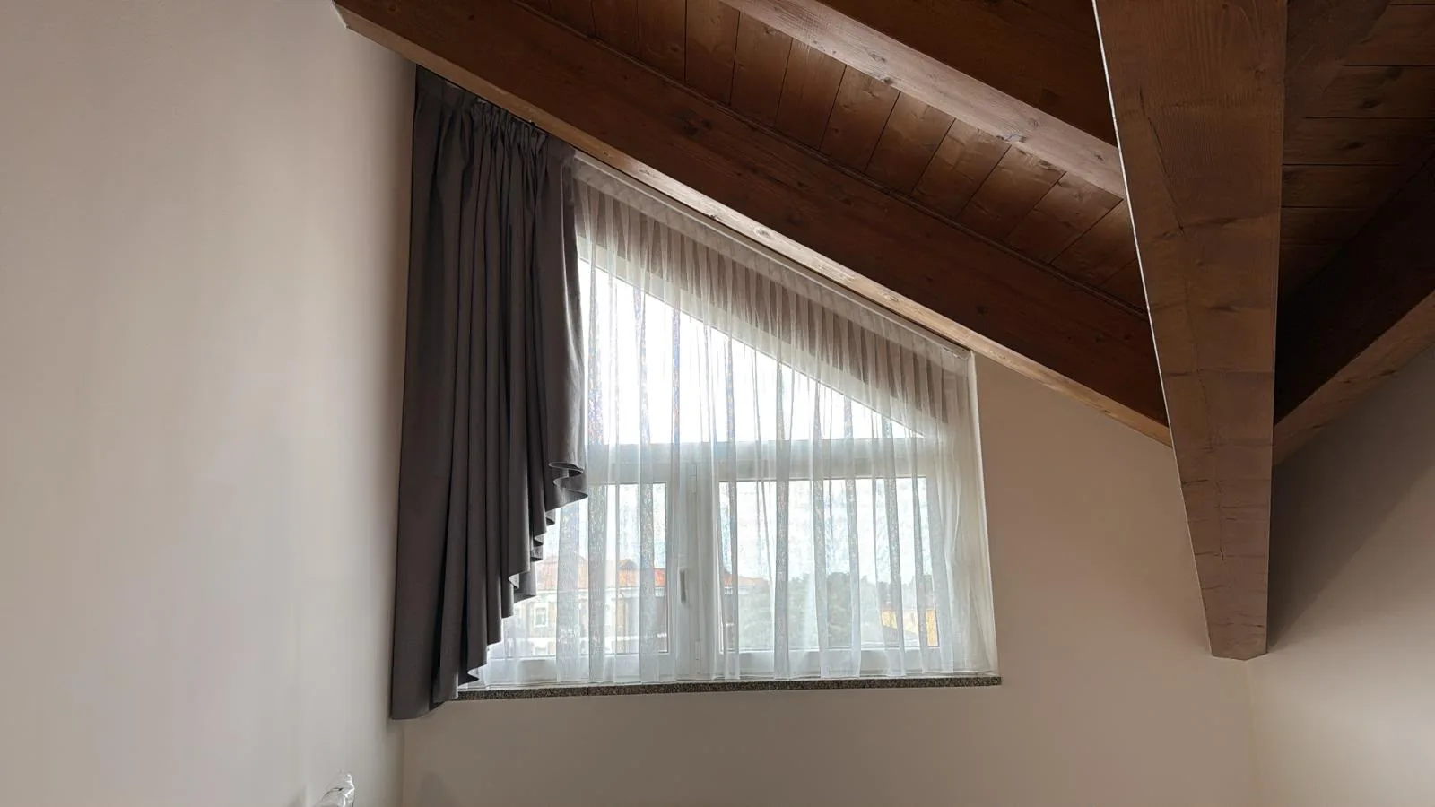 Tenda da interno su finestra di mansarda con travi in legno